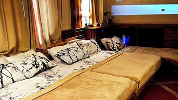 A hotel room with a large bed, a TV screen displaying 'UNKNOWN', and a projector.