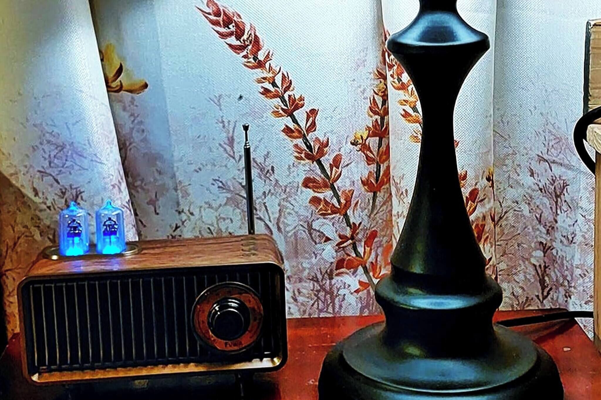 A vintage radio with two illuminated dials and a decorative vase on a table.