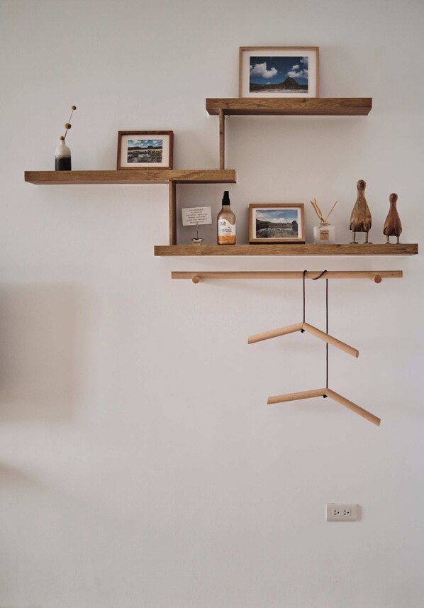 A wall-mounted wooden shelf with various decorative items including a framed picture, a bottle, and two wooden figures. - Here It's home (Lyudao)