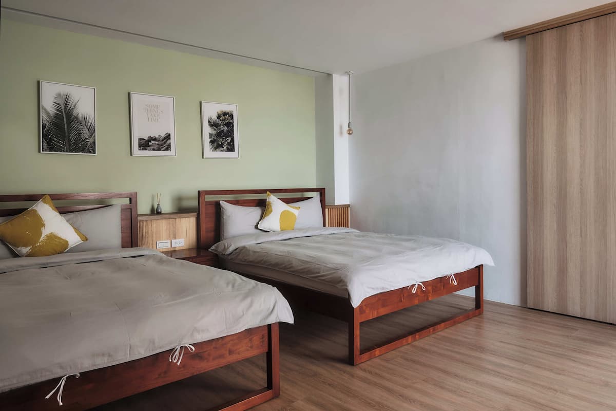 A bedroom with two wooden beds, a nightstand, and wall art.