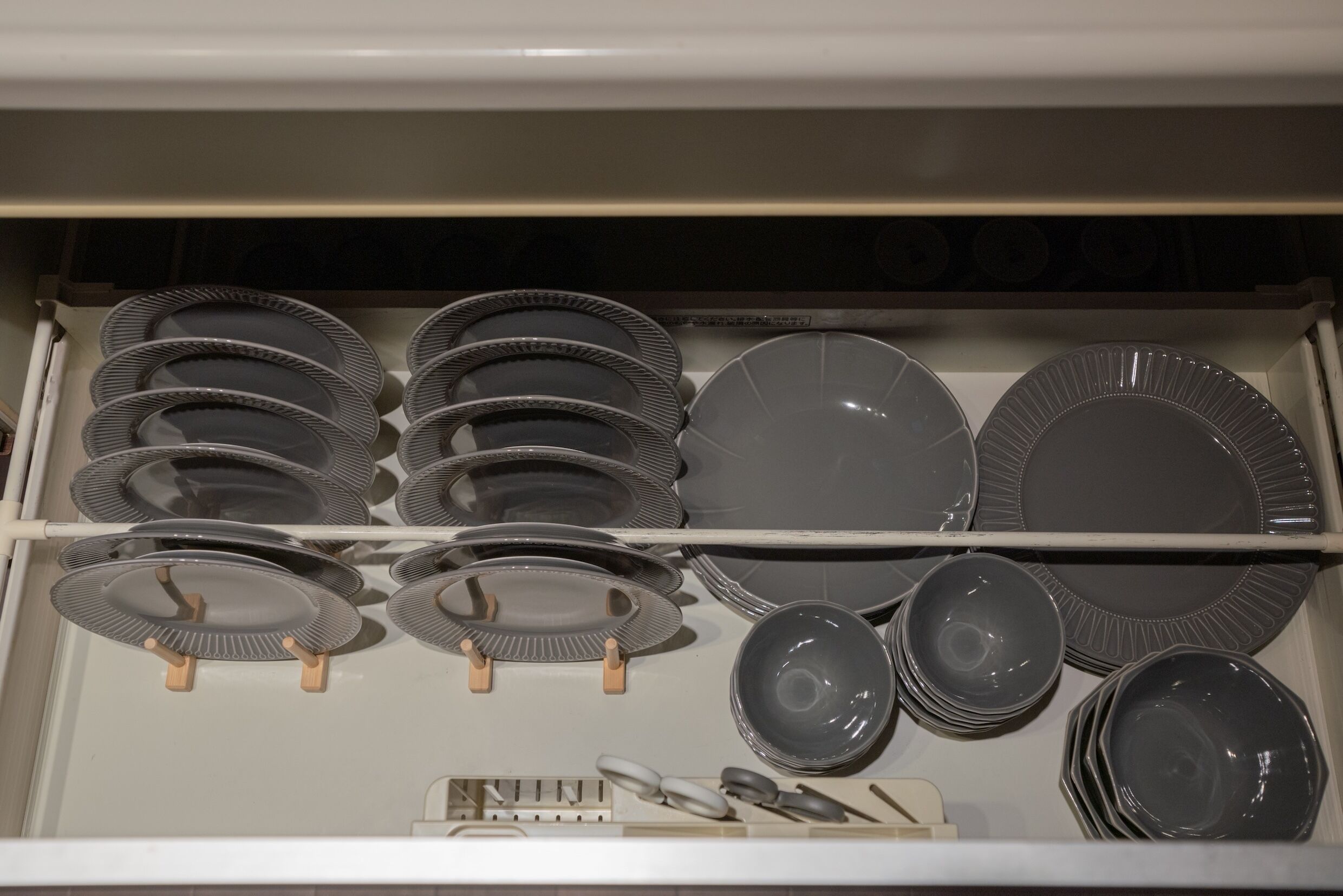 A drawer with neatly organized plates and bowls, including some with handles and others without.