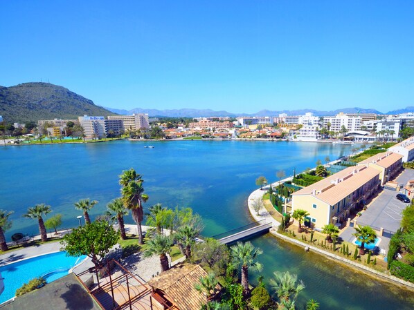 A coastal hotel with a swimming pool, palm trees, and a view of the sea and mountains. - A. The Shell ll NEW, Sea Views and Pool (Alcudia)
