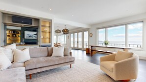 Un salón amplio con un sofá grande, una mesa de centro y vistas al mar a través de amplios ventanales.