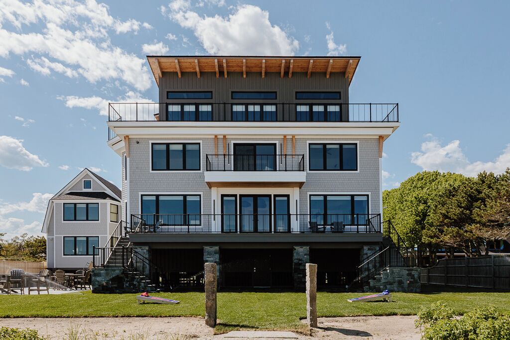 Une maison moderne à deux étages, dotée d’un balcon, d’un porche avant couvert et d’un escalier apparent.