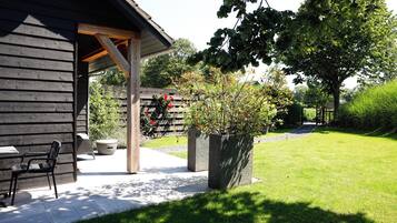 A wooden building with a covered patio area, a bench, and a potted plant.