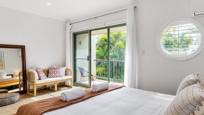 Une chambre à coucher avec un lit, un banc, un miroir et une vue sur l’extérieur.
