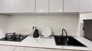 Eine moderne Küche mit weißen Schränken, einem schwarzen Spülbecken, einem Gasherd und einem Wasserkocher.
