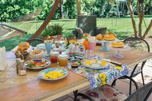 Una mesa al aire libre con diversos alimentos, bebidas y condimentos.