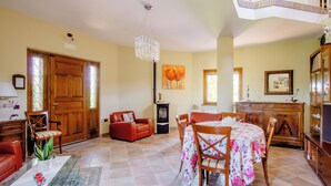 A spacious living area with a dining table, red leather sofa, and a chandelier. - Villa Rosa Lifestyle B&B (Sessa Aurunca)