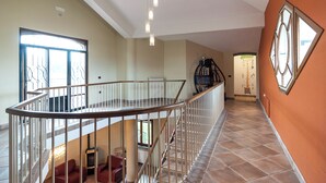 A spacious interior with a high ceiling, a curved staircase, and a view of the outdoors through large windows. - Villa Rosa Lifestyle B&B (Sessa Aurunca)