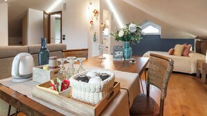 A cozy loft-style room with a wooden dining table, wicker chairs, a sofa, and a bed. - Villa Rosa Lifestyle B&B (Sessa Aurunca)