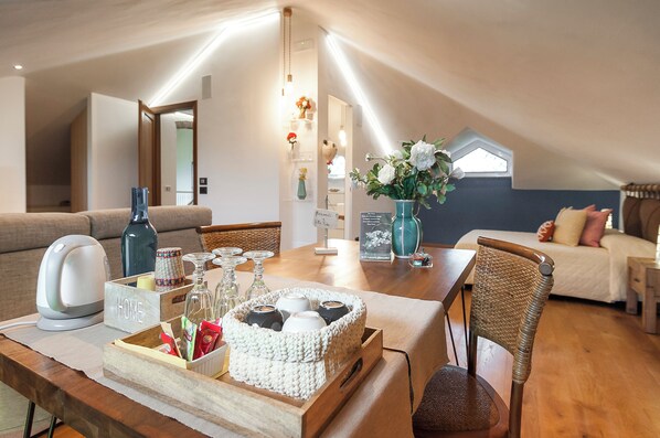 Un acogedor loft con una mesa de comedor de madera, sillas de mimbre, un sofá y una cama.