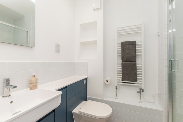 A modern bathroom with a white sink, a toilet, and a glass shower enclosure.