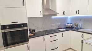 Een moderne keuken met witte kasten, een zwart aanrecht, een ingebouwde oven, een broodrooster en een roestvrijstalen afzuigkap.
