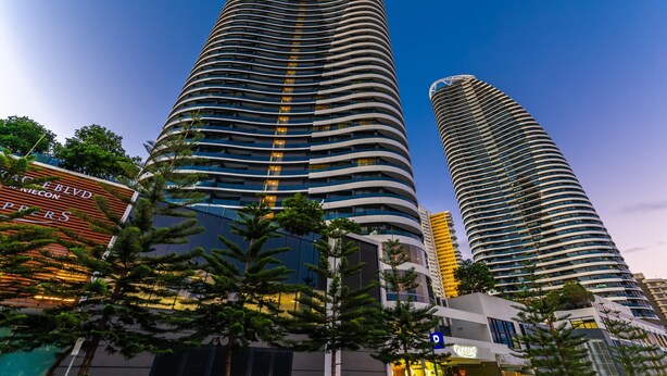 Two tall, curved skyscrapers with a modern design, surrounded by trees and other buildings. - Dream Getaway on Level 29 with Breathtaking Ocean Views in Oracle Broadbeach! (Gold Coast)