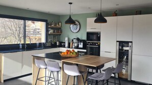 Una cocina moderna con una isla grande, taburetes de bar, un reloj y un refrigerador.