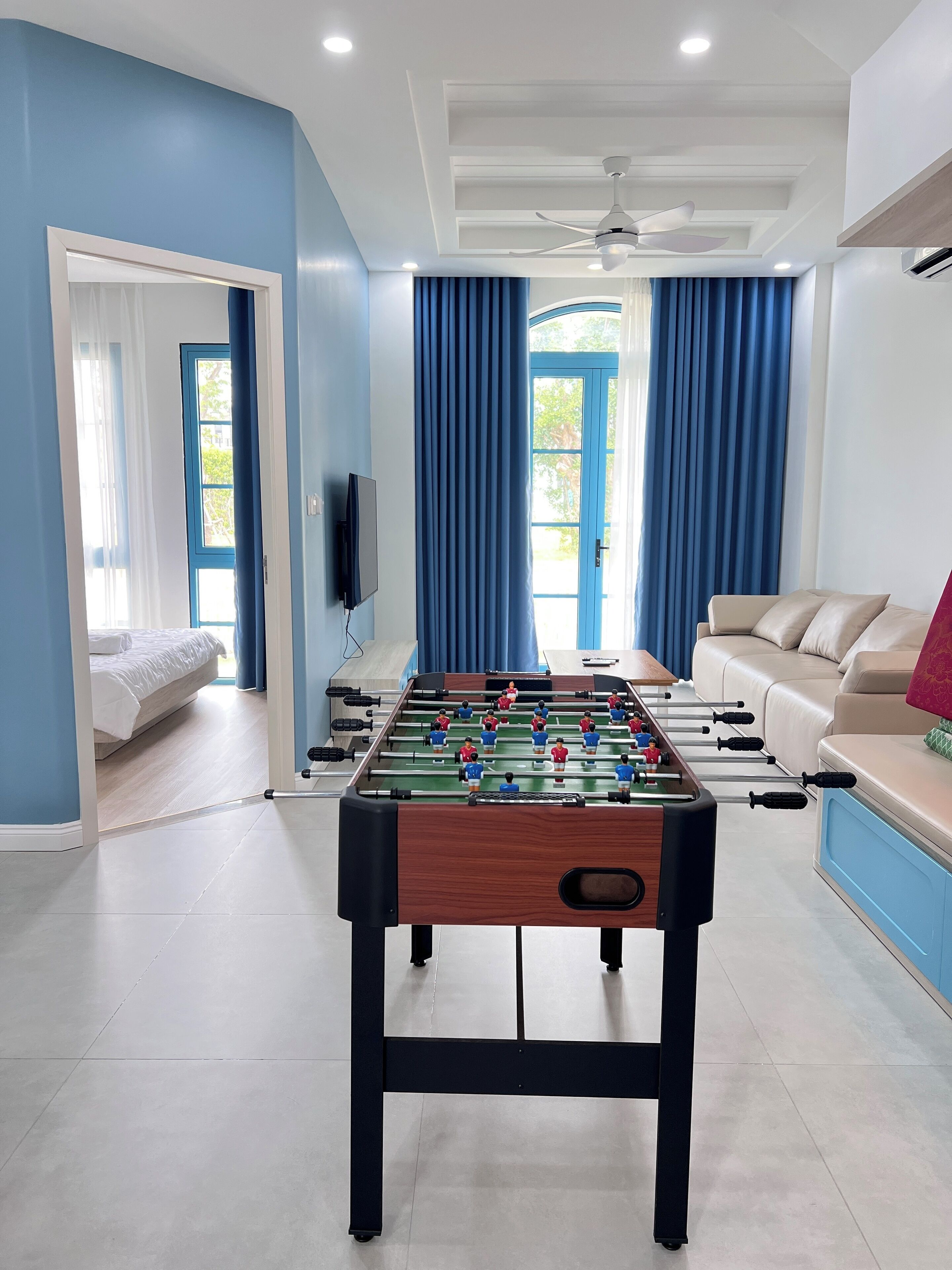 A modern living room with a foosball table, a sofa, and a TV.