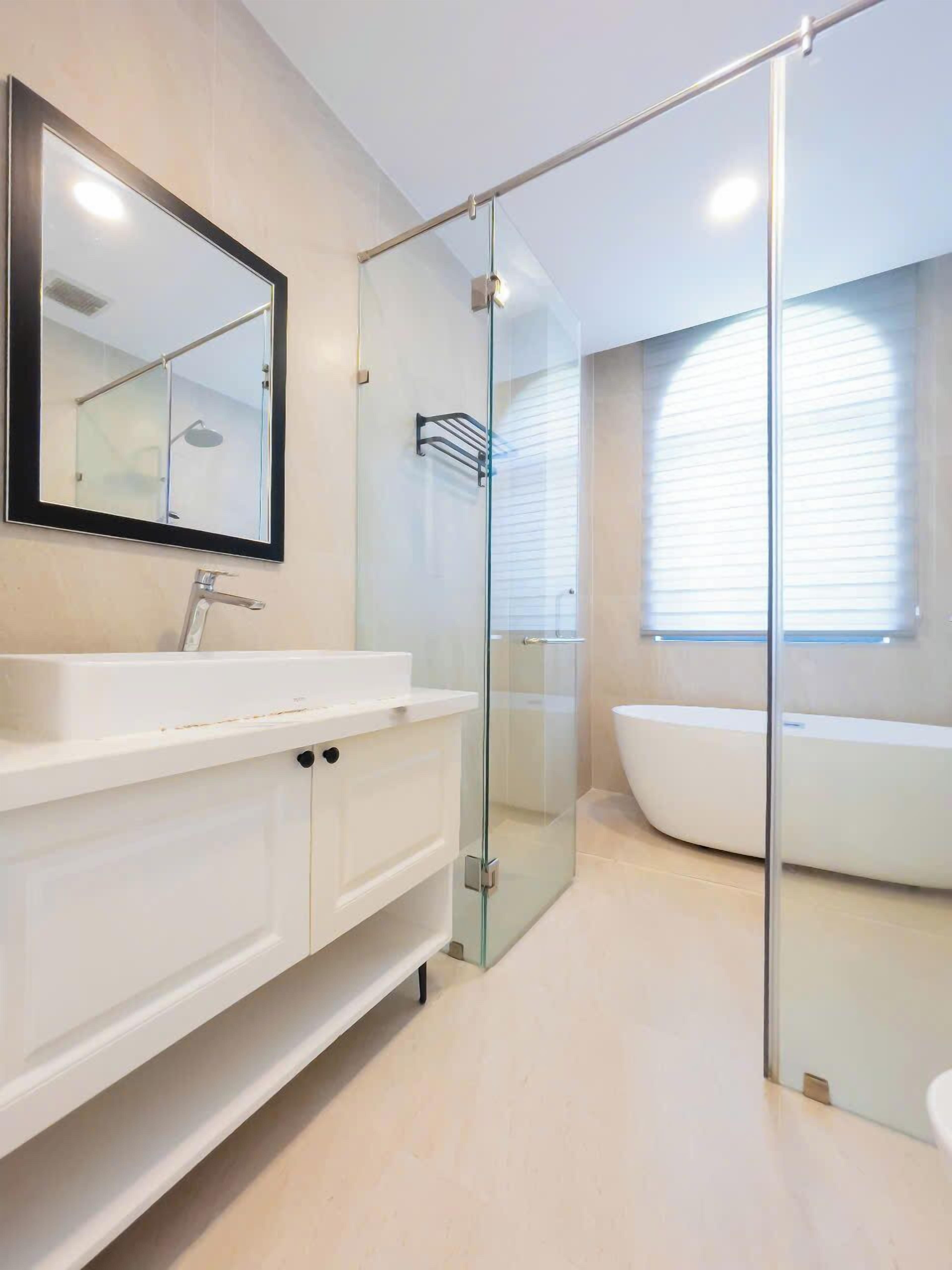 A modern bathroom with a glass-enclosed shower, a large mirror, and a freestanding bathtub.