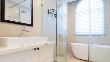 A modern bathroom with a glass-enclosed shower, a large mirror, and a freestanding bathtub.