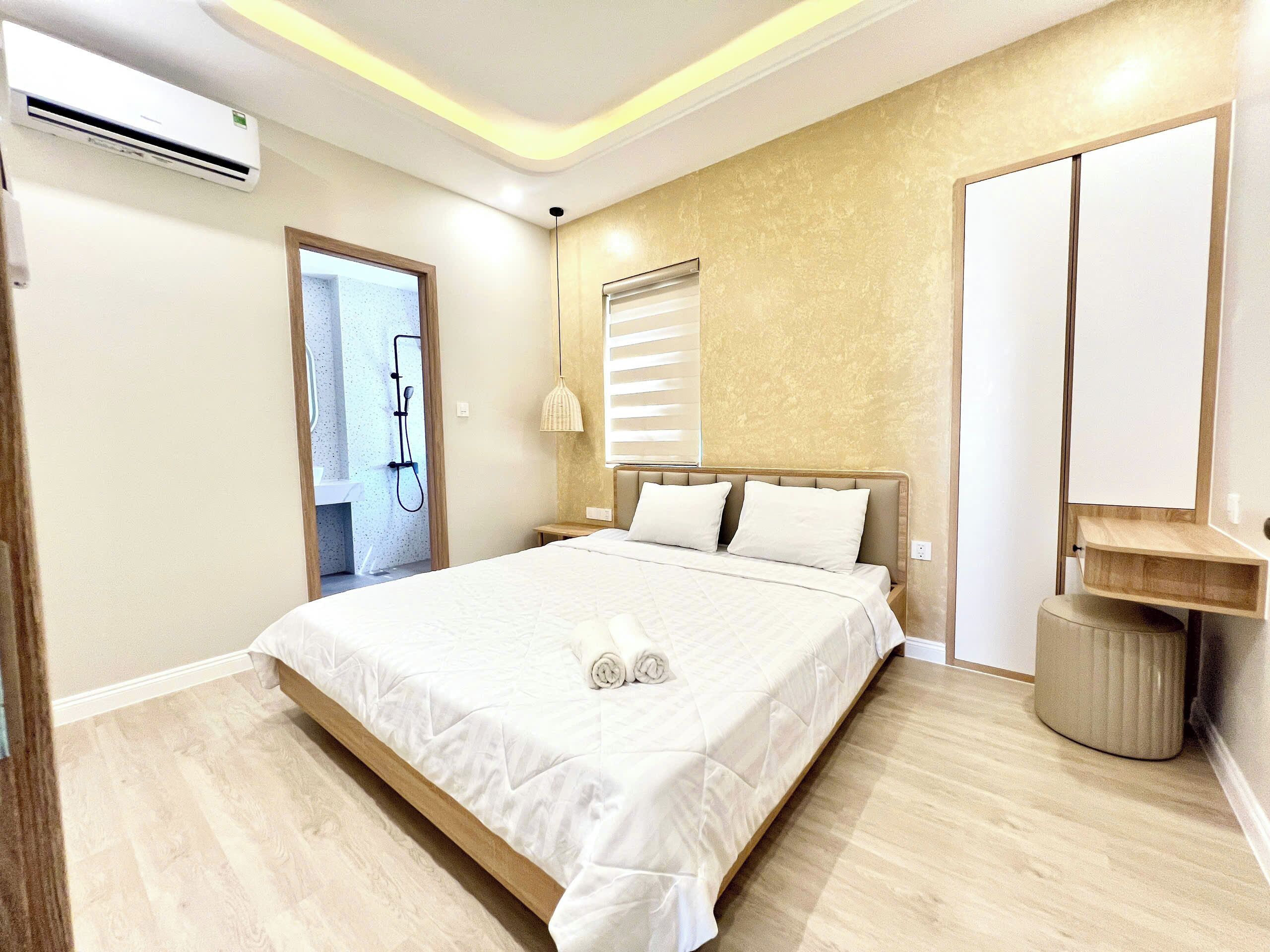 A modern bedroom with a large bed, a bedside table, a mirror, and a built-in bench.