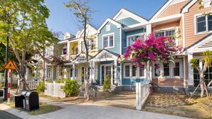 A row of colorful houses with a white picket fence, a mailbox, and a pedestrian crossing sign. - Villa LFP Novaworld Phan Thiet (Tien Thanh)