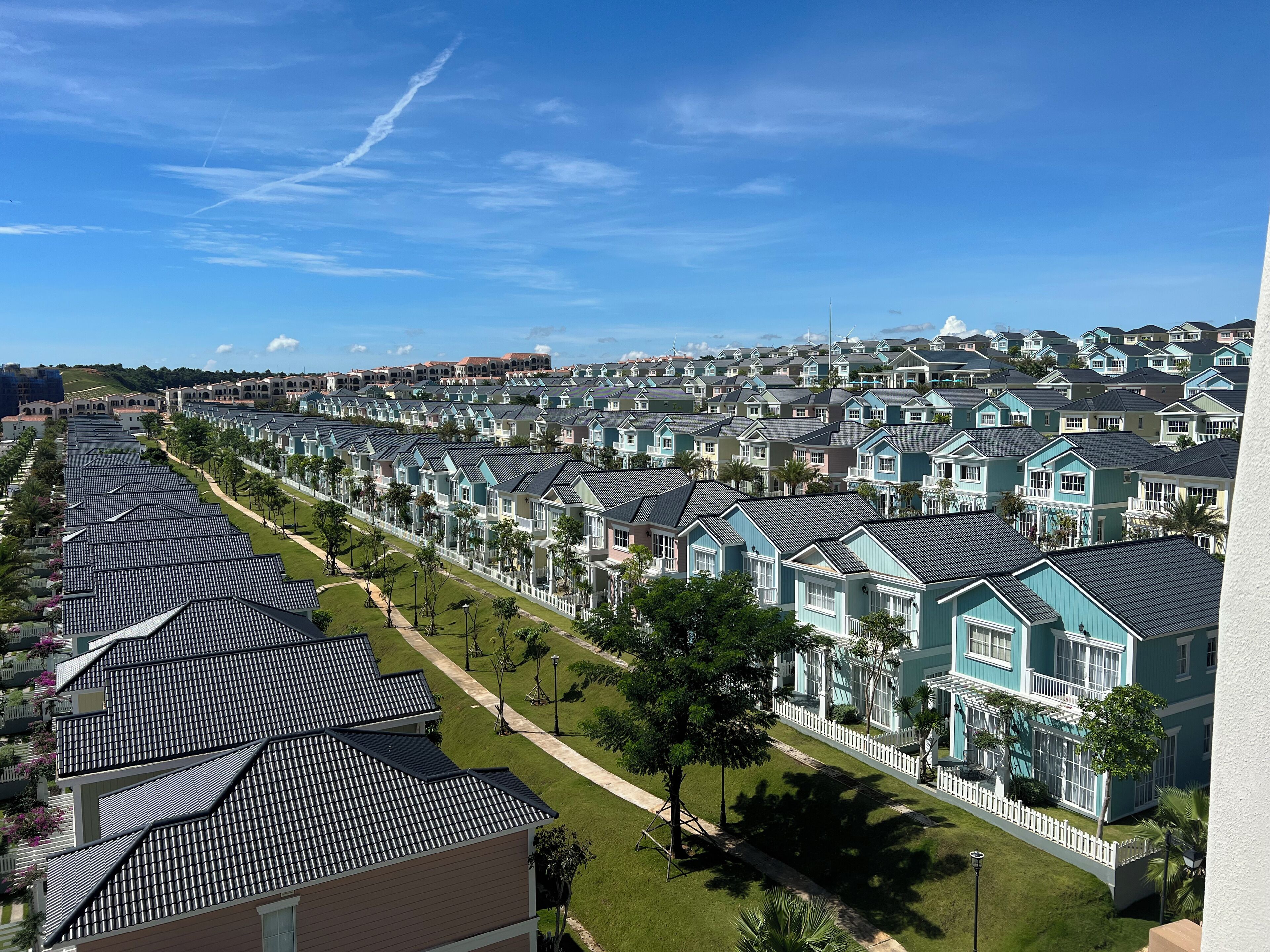 A residential area with rows of houses featuring gabled roofs and white picket fences.