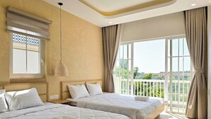 A hotel room with two beds, a large window with curtains, a hanging light fixture, and a view of the landscape. - Villa LFP Novaworld Phan Thiet (Tien Thanh)