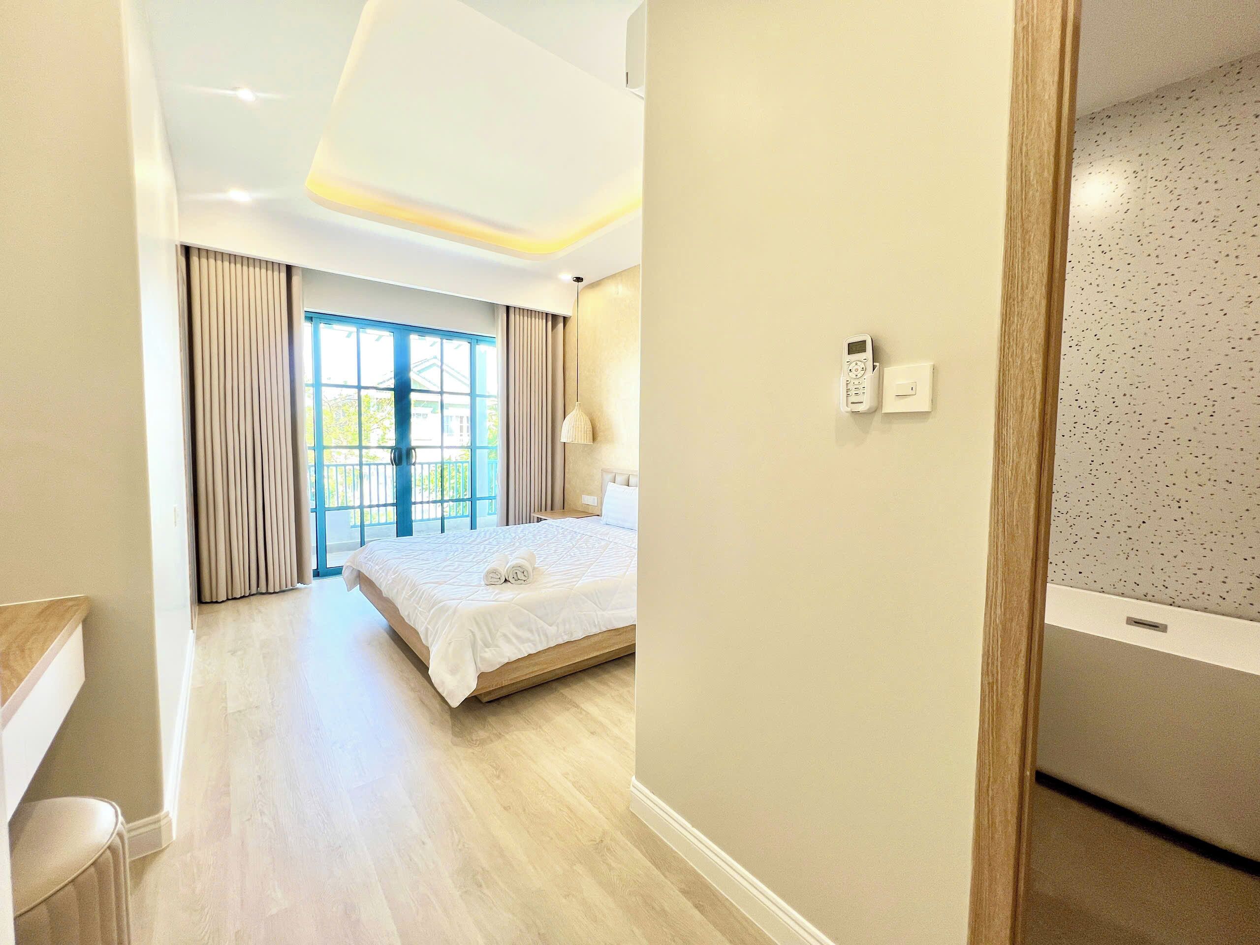 A hotel room with a large bed, a desk, and a view of the outdoors.