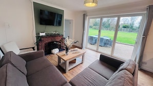 Een woonkamer met een open haard, een flatscreen-tv, een bank en een salontafel.