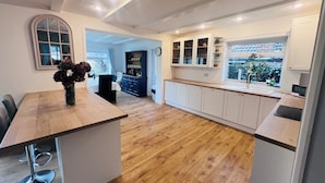 Een moderne keuken met houten vloeren, witte kasten en een centraal eiland met een bloevas.
