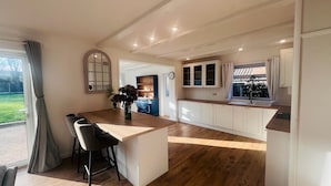 Een moderne keuken met een centraal eiland, houten vloeren en uitzicht op de omgeving.