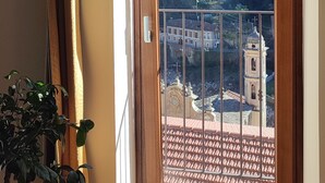 Une pièce avec vue sur une colline, une porte en bois, une plante en pot et un sol carrelé.