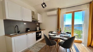Una cocina moderna con armarios blancos, un grifo negro y un comedor con una mesa para dos.