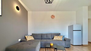 Una sala de estar moderna con un sofá seccional gris, una mesita con una vela y una alfombra blanca y mullida.