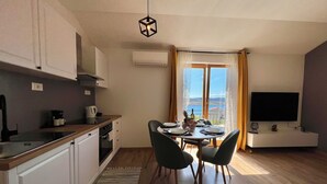 Una cocina moderna con comedor, televisor y vista al mar.
