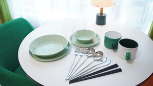A round table with a white tablecloth, green plates, a green mug, a green cup, a spoon set, chopsticks, and a lamp. - Rio Grande Nishi-Shinjuku (Tokyo)