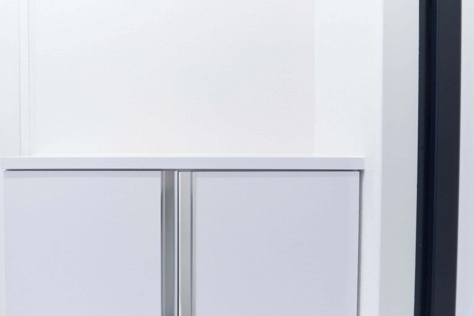 A white interior wall with a textured surface and a door with a metallic handle.