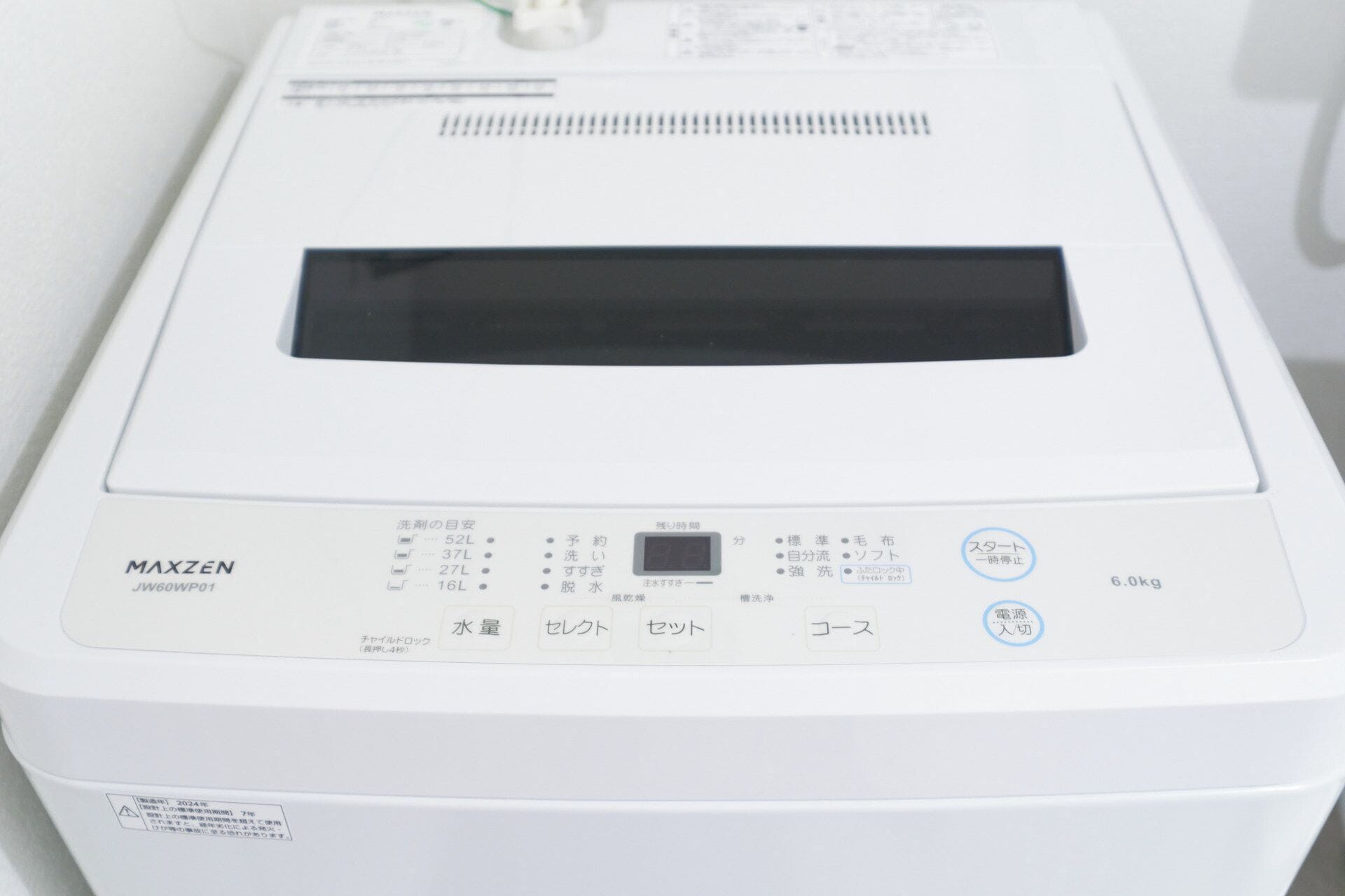 Una lavatrice bianca con etichette giapponesi, un display digitale e una capacità di carico di 6,0 kg.