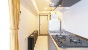 A compact kitchen with a gas stove, a microwave, and a refrigerator. - Rio Grande Nishi-Shinjuku (Tokyo)
