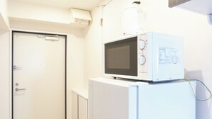 A white microwave on a white refrigerator in a narrow hallway. - Rio Grande Nishi-Shinjuku (Tokyo)