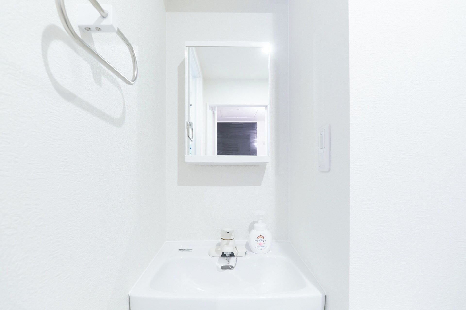 Une salle de bain blanche avec un lavabo, un miroir et une fenêtre.
