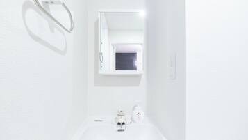 A white bathroom with a sink, a mirror, and a window.