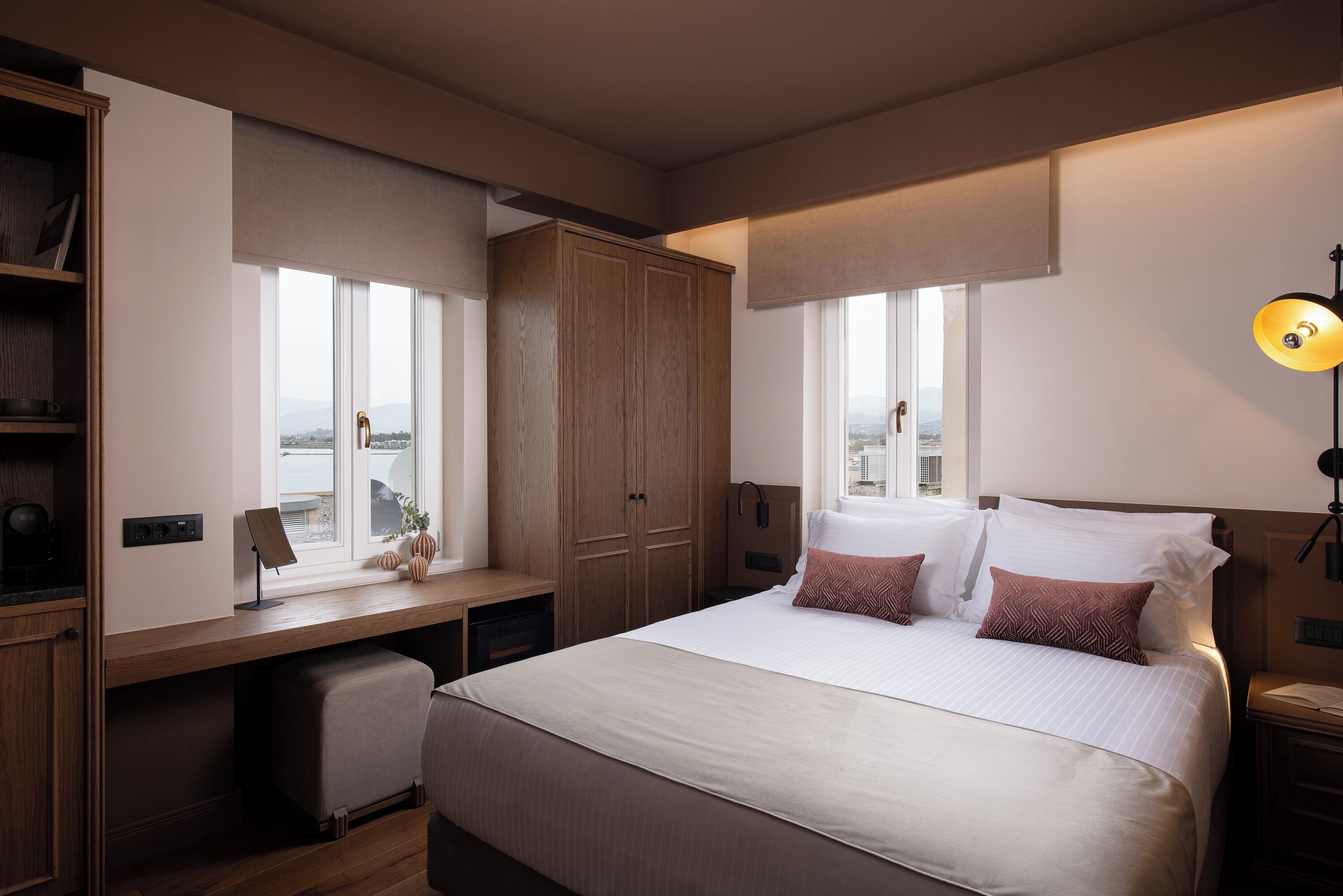 Habitación de hotel con una cama grande, un escritorio, un armario y vistas a la ciudad.