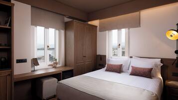 Habitación de hotel con una cama grande, un escritorio, un armario y vistas a la ciudad.
