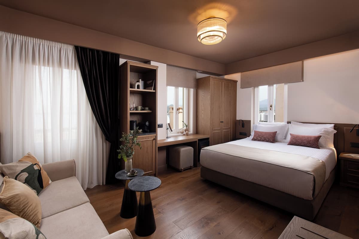 Ett hotellrum med en säng, ett skrivbord, en soffa och ett litet bord.