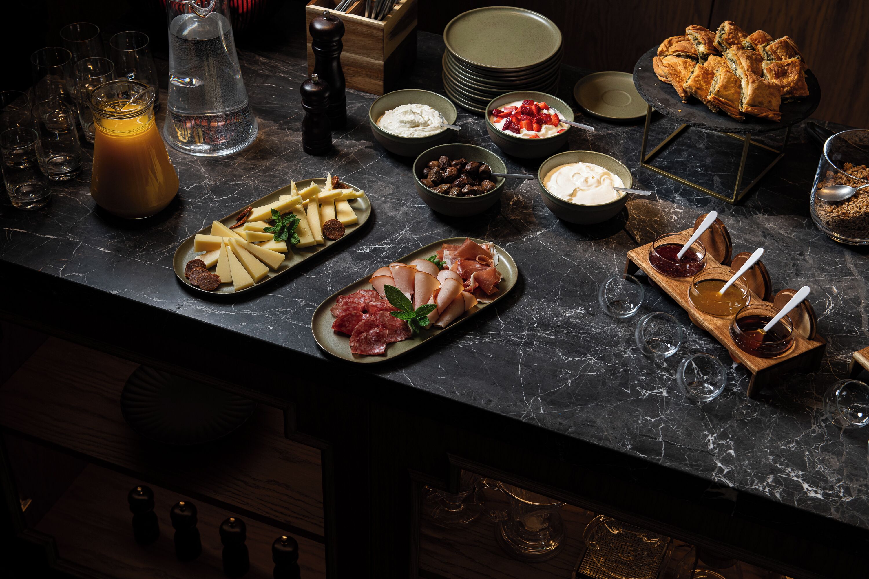 A well-organized buffet with various cheeses, meats, and spreads.