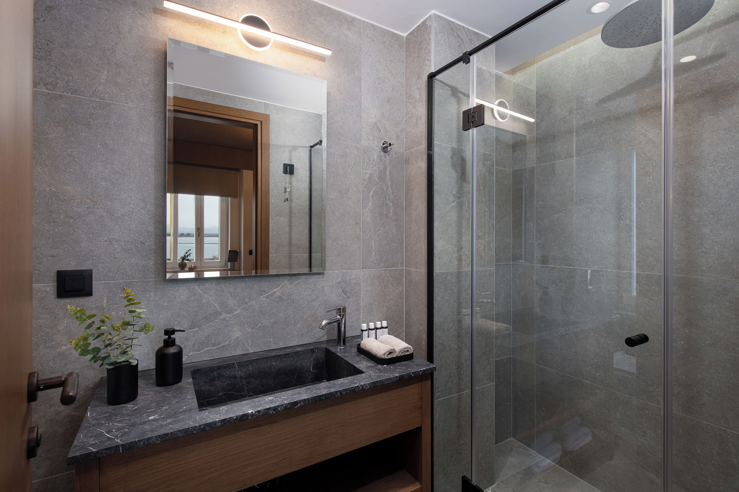 Une salle de bain moderne avec une douche à parois de verre, un lavabo en marbre et un grand miroir.