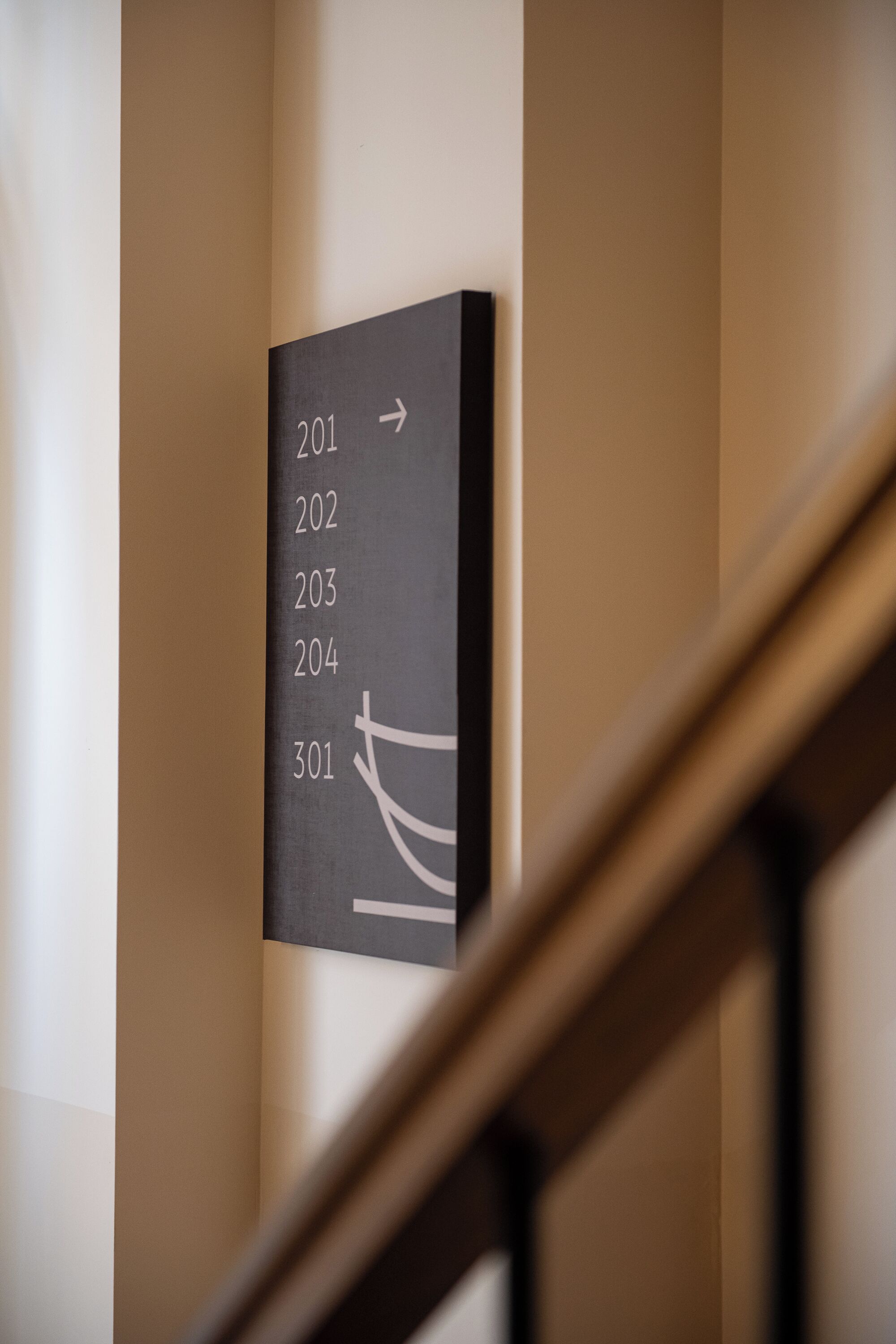 A wall-mounted sign with room numbers 201 to 301, indicating a hotel or apartment building.