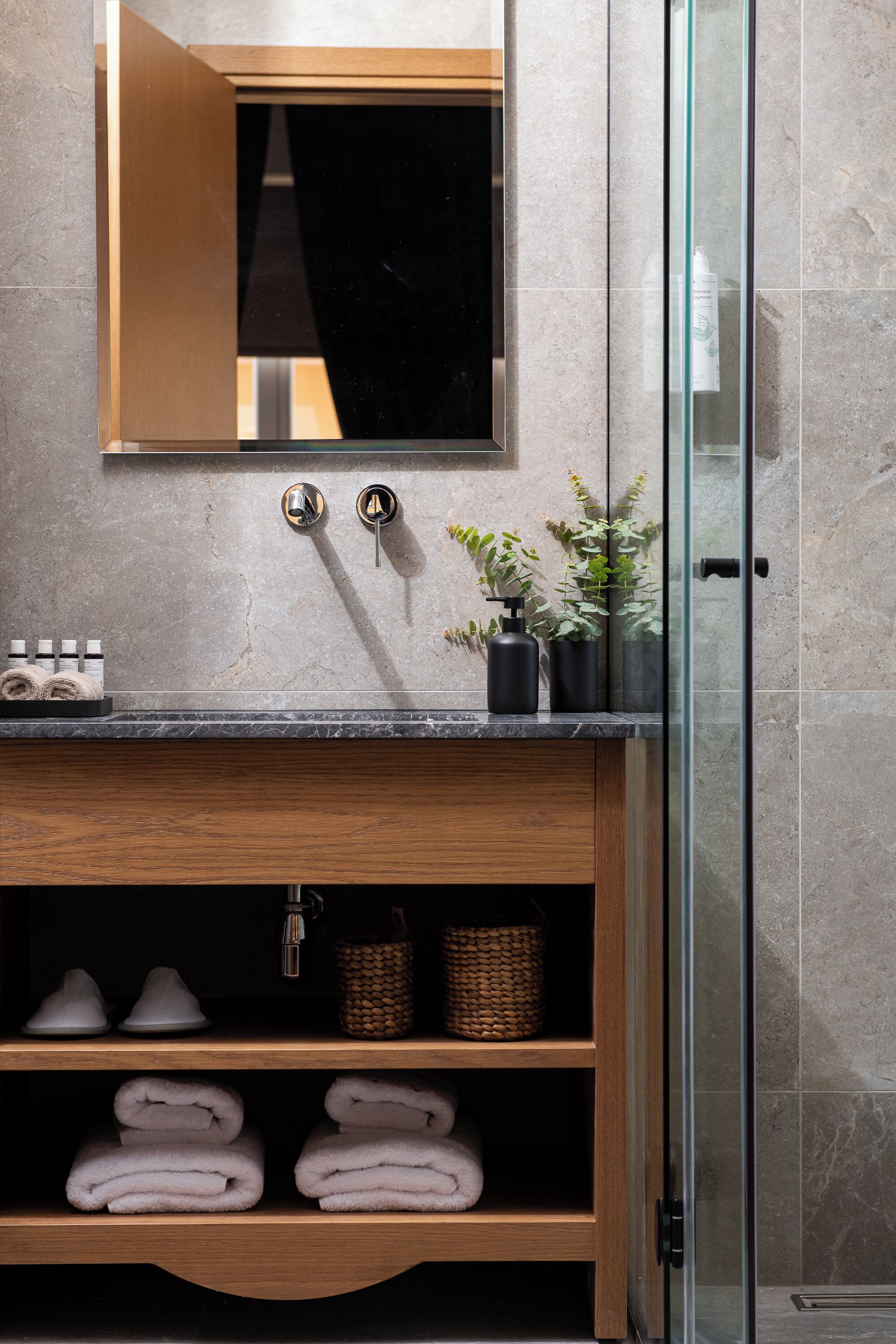 Une salle de bain avec un lavabo en marbre, un meuble-lavabo en bois et une cabine de douche en verre.