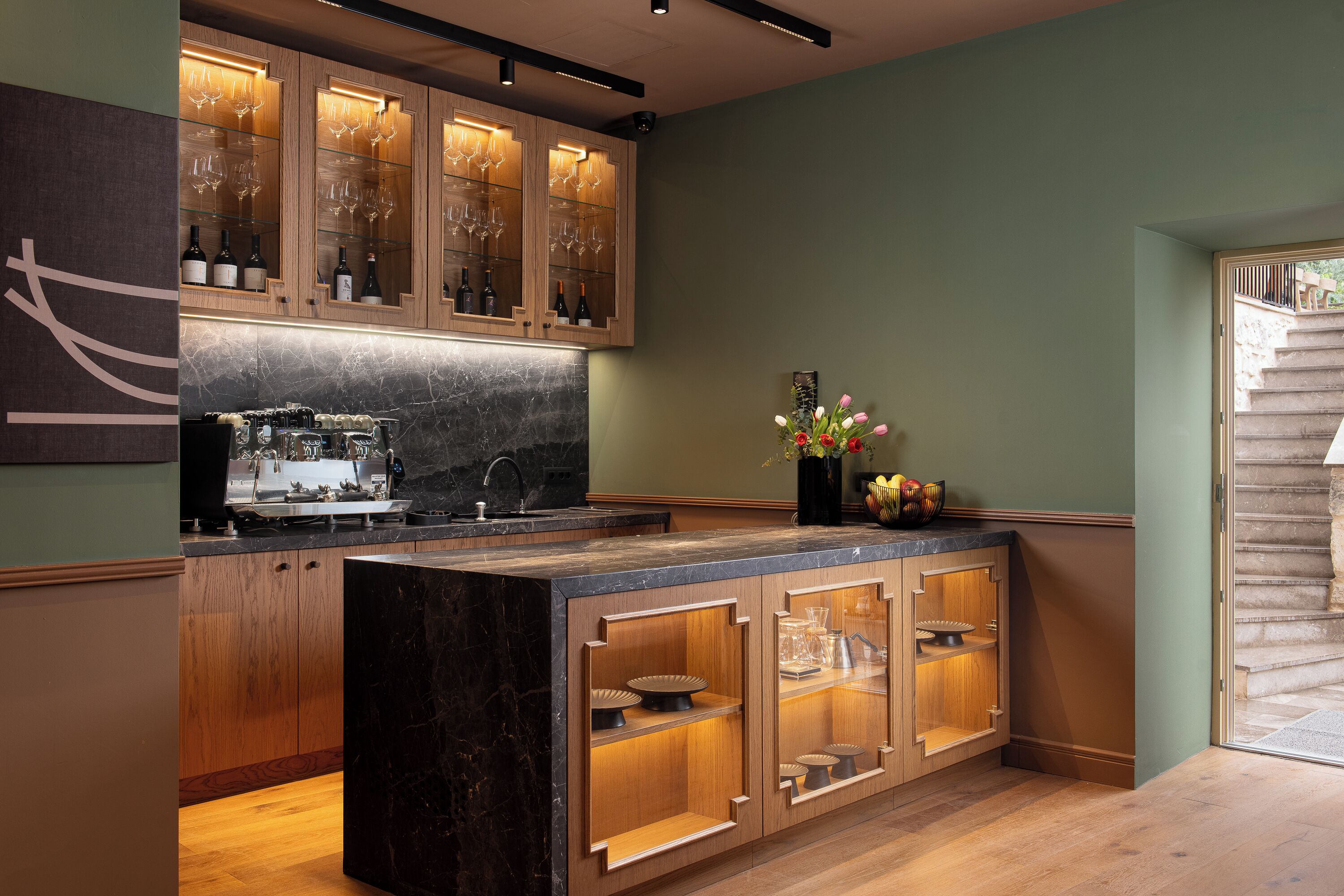 A modern kitchen with wooden cabinets, a marble countertop, and a built-in wine rack.